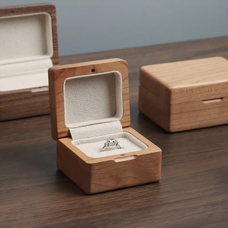 Square wooden ring box with silver stone ring in cream velvet interior