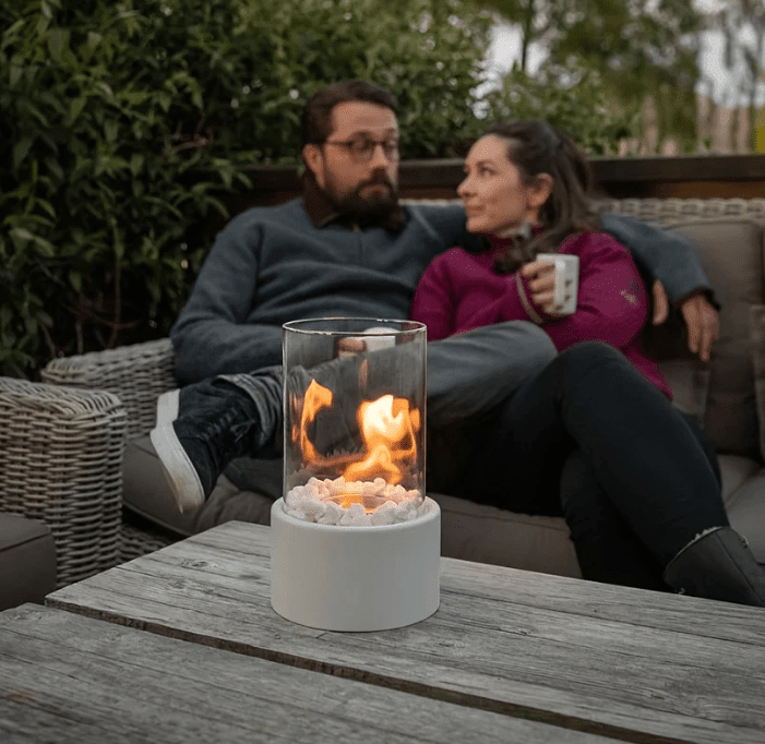 White concrete outdoor fire bowl on patio table with people relaxing