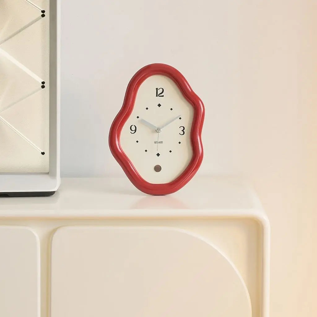 Bold cherry red wavy table clock resting on curved white surface