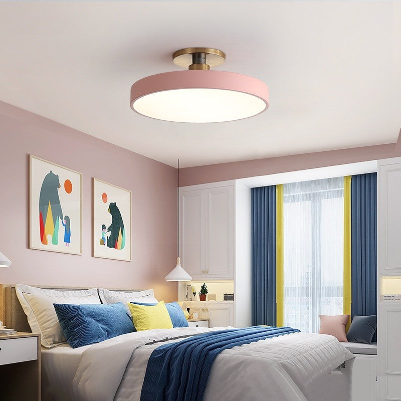 Maintained House Macaron Drum LED Ceiling Light - Pink above a bed with blue bedding