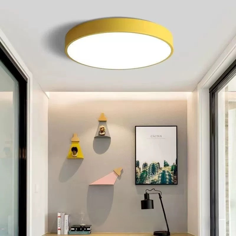 Maintained House Macaron Flush Mount LED Ceiling Light - Yellow in a bright room with wall shelves