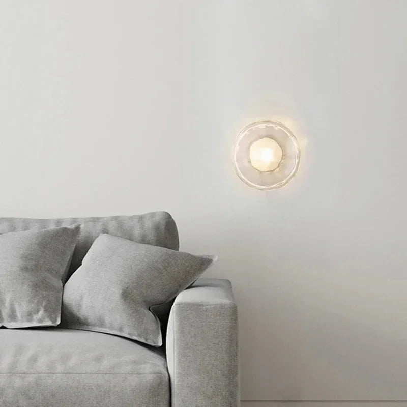 Maintained House Nordic Rippled Glass Wall Sconce - Single Disc in Clear Glass / Brass above a gray sofa