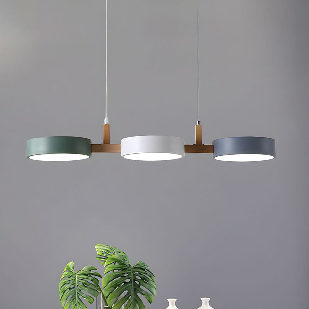 Maintained House Nordic Wood Drum LED Pendant - Green, White and Gray drums above a marble dining table