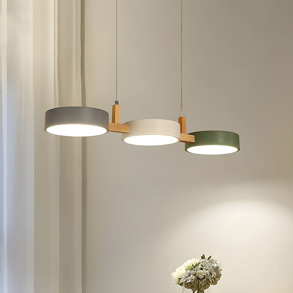 Maintained House Nordic Wood Drum LED Pendant - Gray, Cream and Green drums lit warm against a beige wall