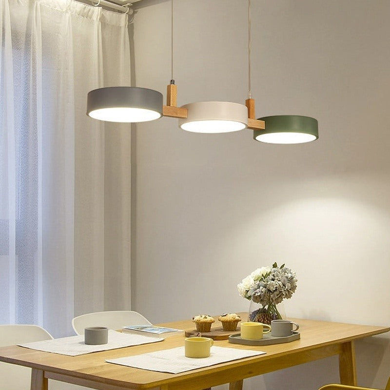 Maintained House Nordic Wood Drum LED Pendant - Gray, White and Green drums over a breakfast table