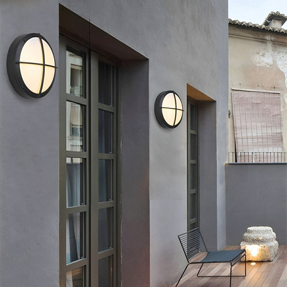 Maintained House Round Outdoor LED Wall Light - Cross style on a gray house by a patio door