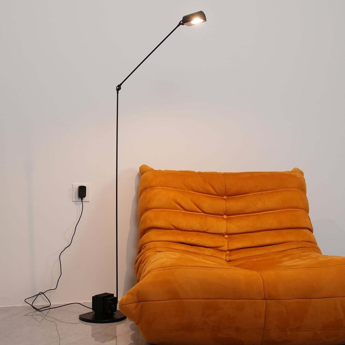 Maintained House Slim Swing Arm LED Floor Lamp - Lit beside a lounge chair